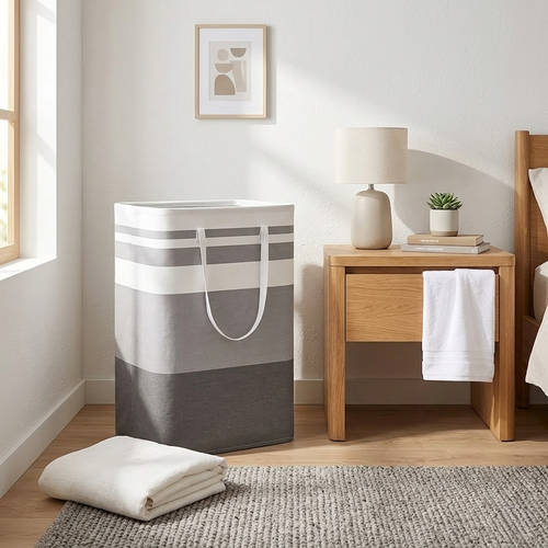 Gray and white striped laundry basket in a bedroom with wooden nightstand and folded white towels.